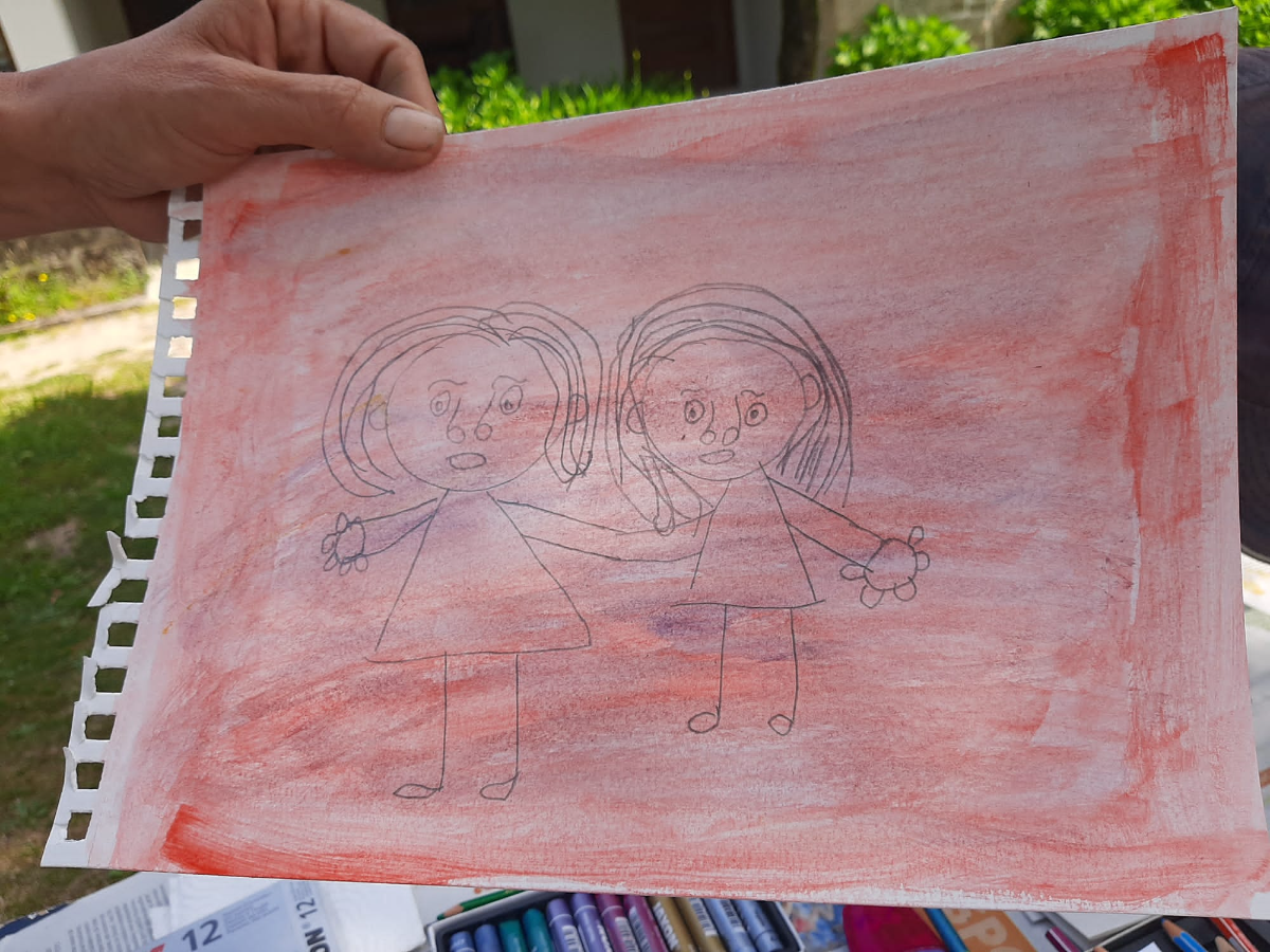 Desenho de duas figuras sobre fundo vermelho, seguro à mão