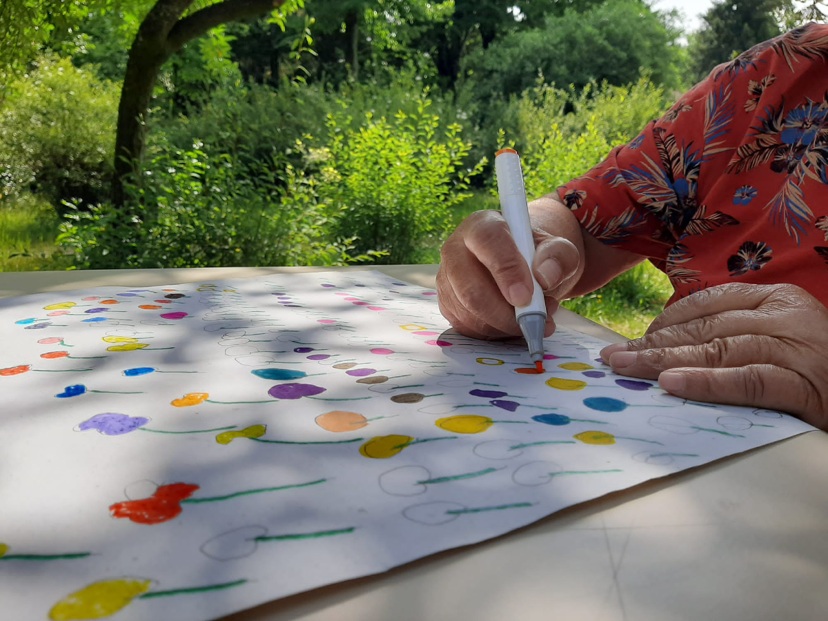 Mão a pintar flores a marcador numa folha grande