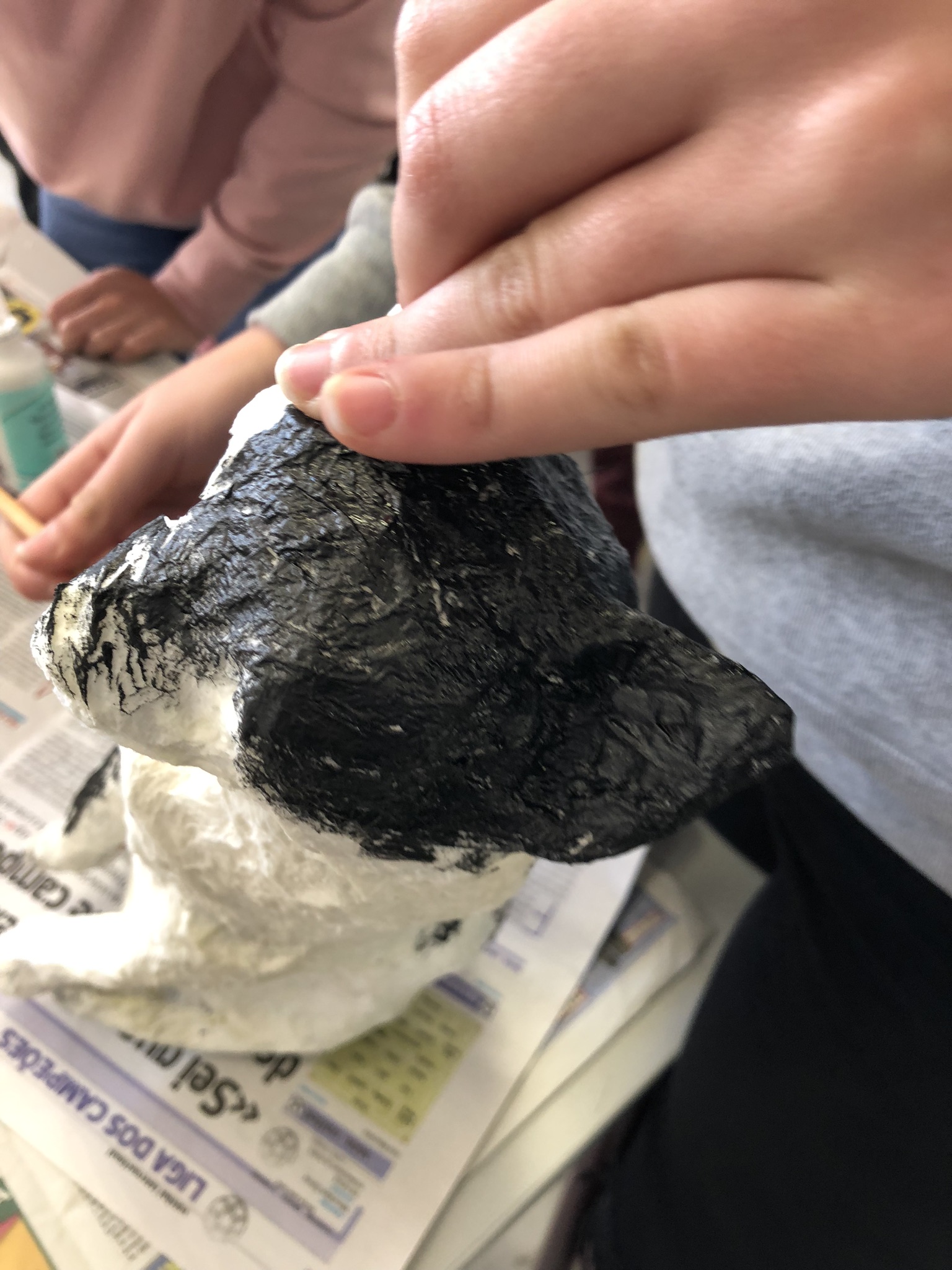 Mãos a segurar uma cabeça pintada de preto e branco