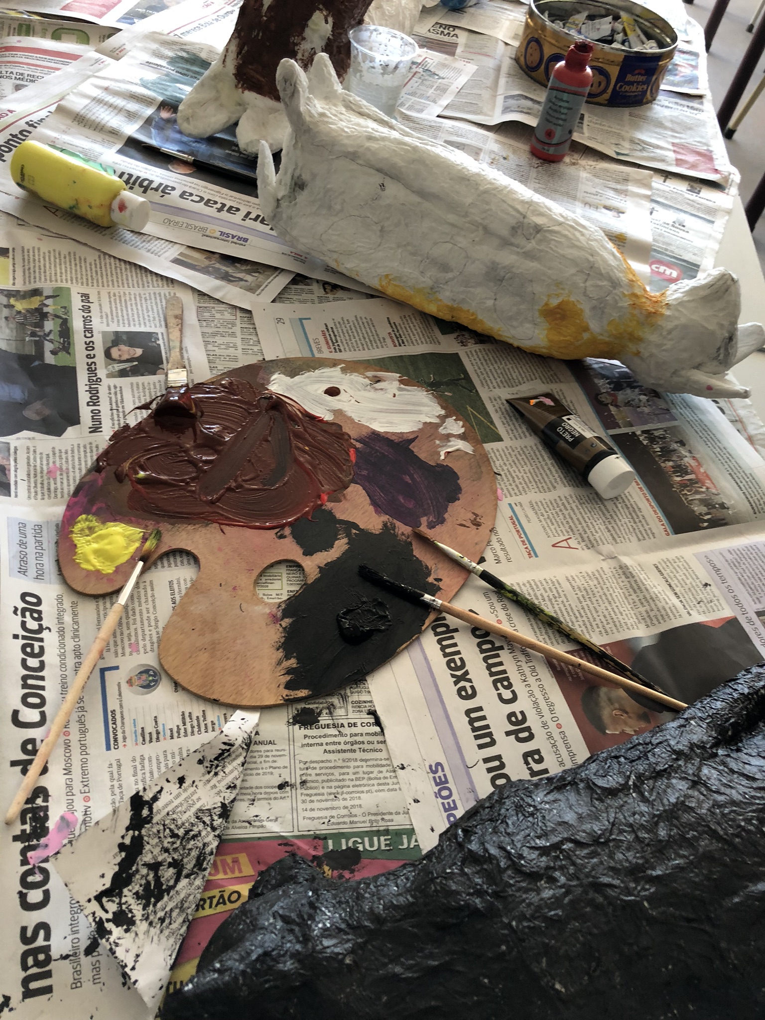 Mesa coberta de jornal com cabeças de animal em papel colado